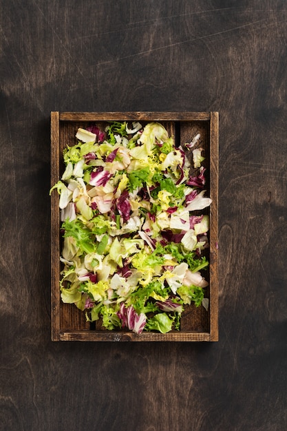 Photo mix fresh leaves of arugula, lettuce, spinach, beets for salad in wooden box on wooden rustic.