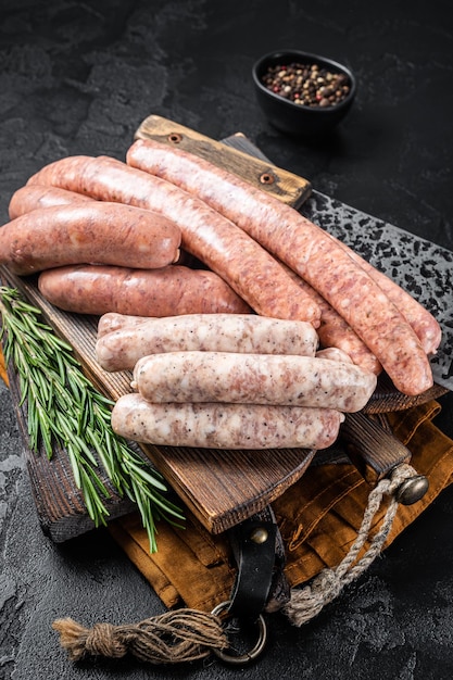 Mix fresh raw sausages Beef pork lamb and chicken mince meat sausages on a butcher cutting board with spices Black background Top view