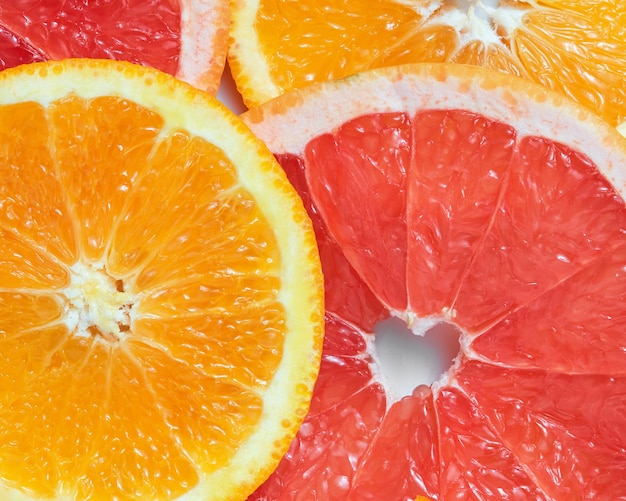 Mix of fresh sliced oranges and grapefruits on white surface