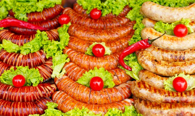 Mix grilled sausages on pan with herbs, tomato and spices, outside.