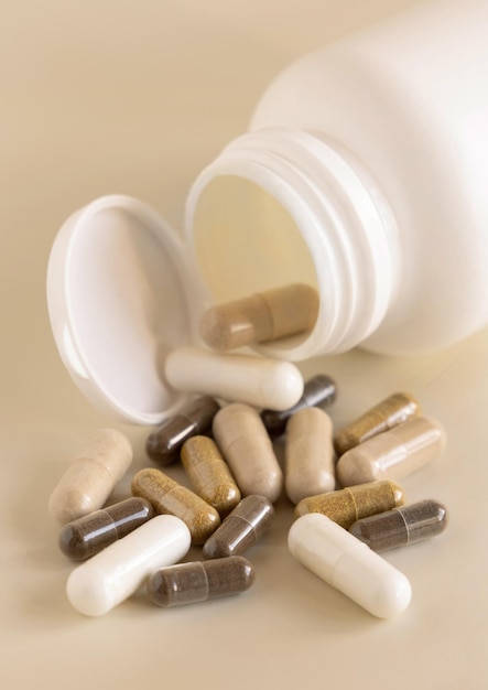 Mix of medical capsules in a bottle on light beige close up Taking dietary supplements