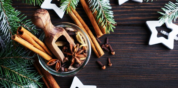 Mix of mulled wine seasonings in a jar of anise, cardamom, allspice, cinnamon sticks, cloves on a wooden dark background. Place for text