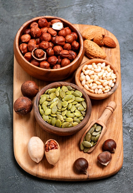 Mix of nuts on board closeup. Assorts of nuts. Filbert, peanuts, almonds, peacsn nuts, pumpkin seed, pine seed on board closeup.