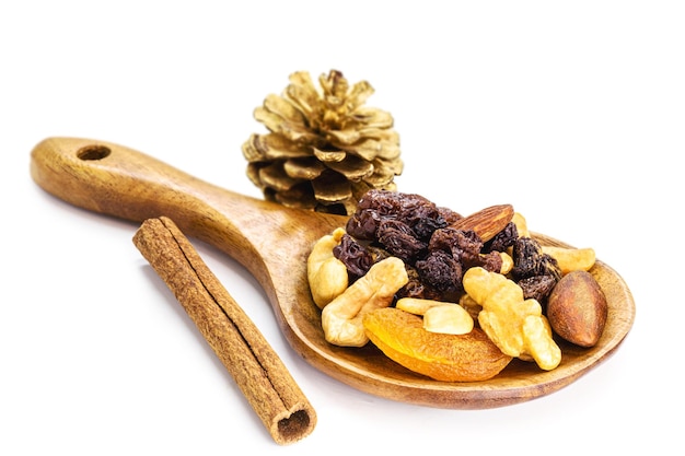 Mix di noci e frutti di natale disidratati in un cucchiaio di legno rustico noci del brasile albicocche uvetta prugne e noci