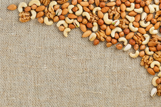 Mix of nuts lying on a  of brown cloth burlap.