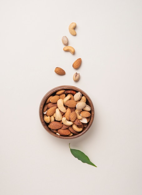 Mix of nuts on wooden bowl on light background