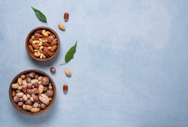 Photo mix of nuts on wooden bowls on blue background