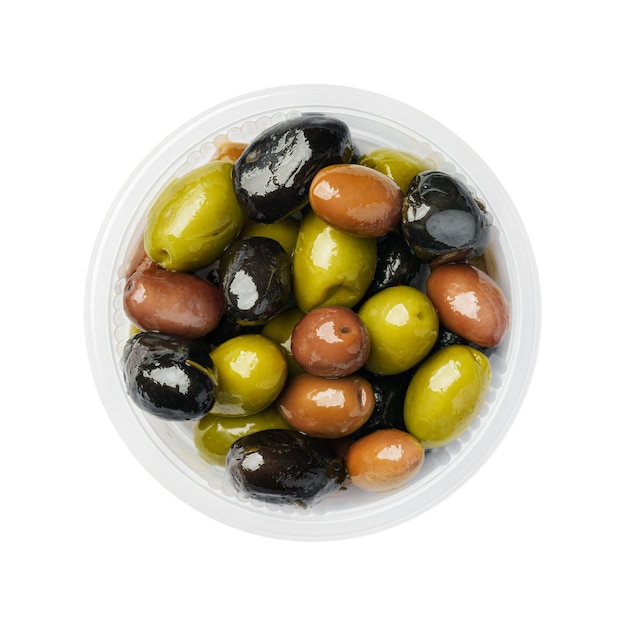 Фото Смесь зеленых коричневых и черных оливок в пластиковой тарелке на белом фоне