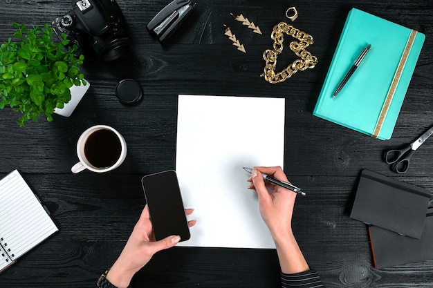 Mix of office supplies and gadgets on a wooden desk background view from above