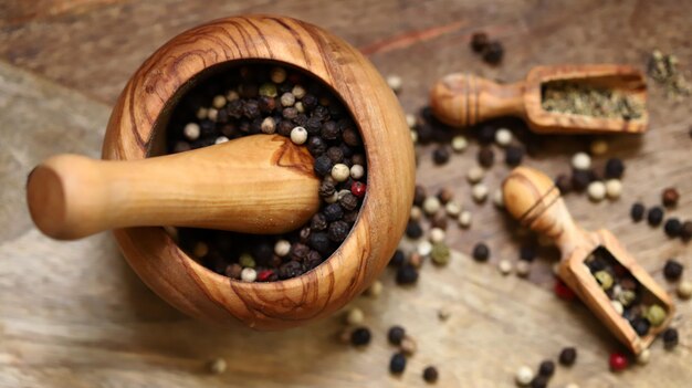Mix of peppercorns in a wooden mortar and wooden spatulas