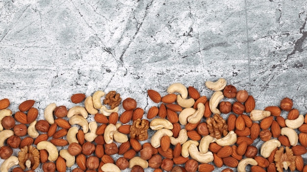 Mix of raw nuts on gray stone background.