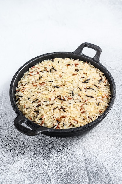 Mix rice in a cast-iron pan. White background. Top view.