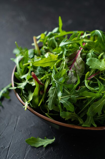 샐러드 채소를 섞습니다. 검은 그릇에 Arugula, 양상추, 시금치