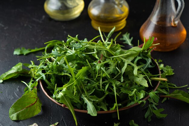 샐러드 채소를 섞습니다. 검은 그릇에 Arugula, 양상추, 시금치