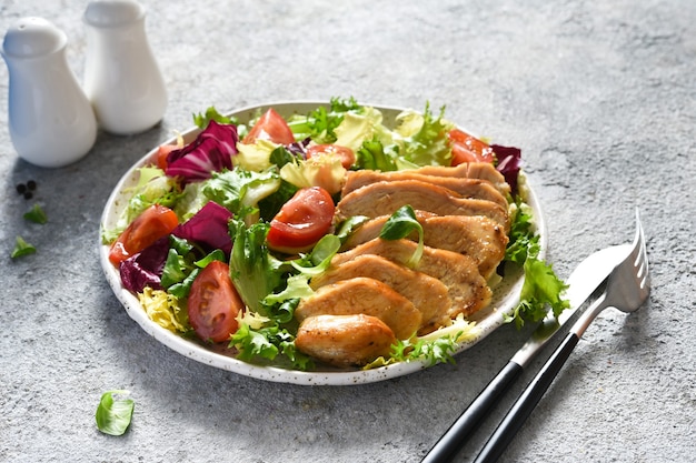 Mix salad with tomatoes and chicken fillet in a plate  .