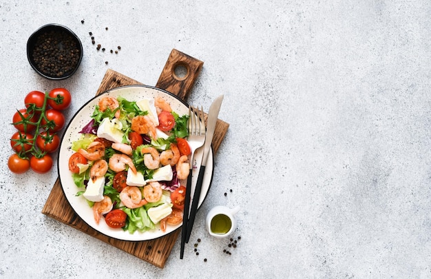 Mix salade met garnalen brie kaas en tomatensaus op een grijze betonnen achtergrond bovenaanzicht