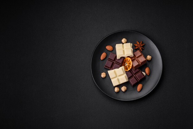 A mix of several types of delicious sweet chocolate broken into cubes on a black plate