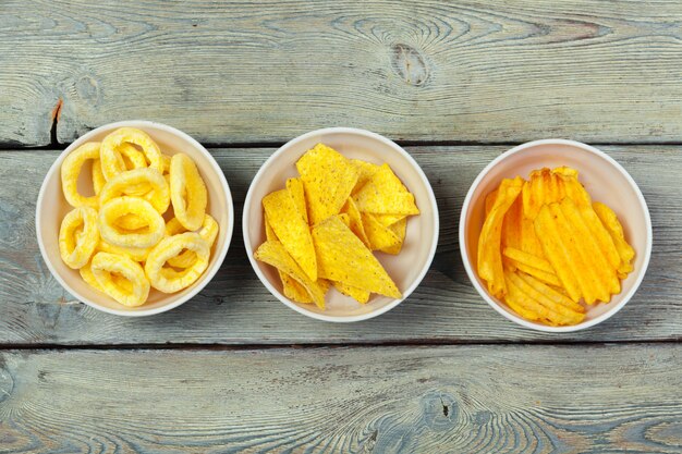 Mix of snacks : pretzels , crackers , chips  and nachos on the table