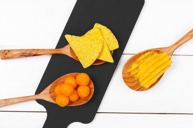 Mix of snacks : pretzels , crackers , chips  and nachos on the table