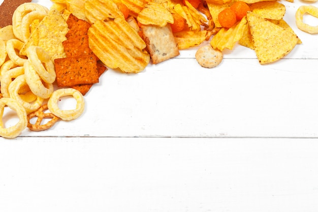 Photo mix of snacks : pretzels , crackers , chips  and nachos on the table