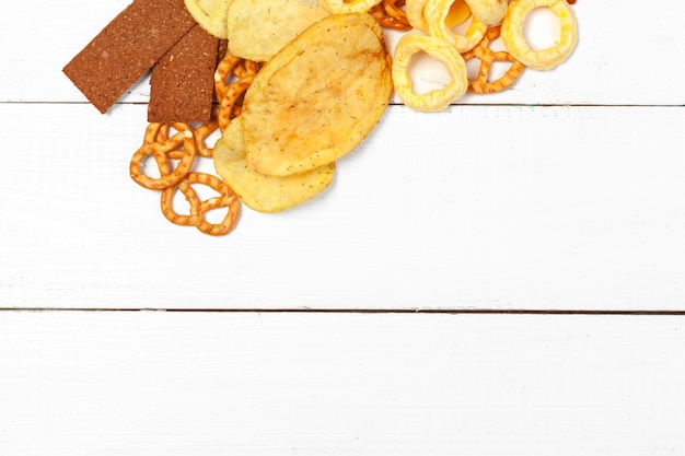 Mix of snacks : pretzels , crackers , chips  and nachos on the table