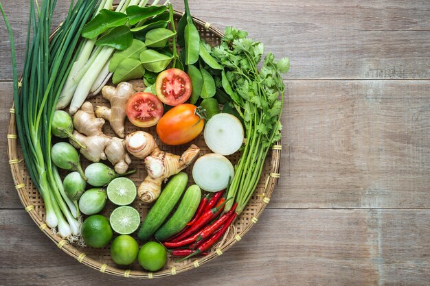 Mix of Thai vegetable in bamboo tray on wooden background.