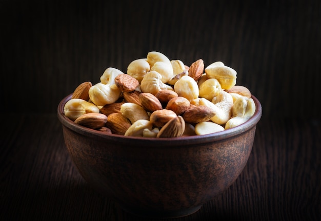 Mix van cashewnoten en amandelen in een kleiplaat op een donkere houten achtergrond