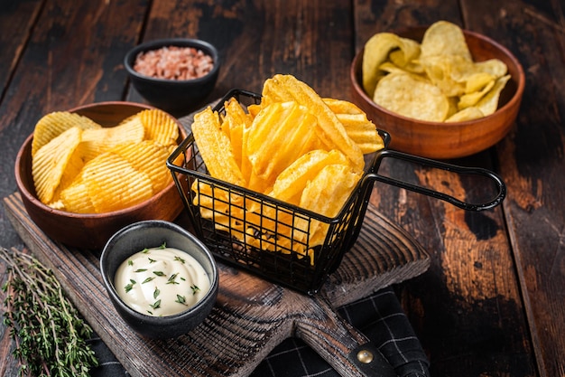 Mix van Crinkle Potato chips geserveerd met dipsaus en zeezout Houten achtergrond Bovenaanzicht