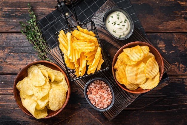 Mix van crinkle potato chips geserveerd met dipsaus en zeezout houten achtergrond bovenaanzicht