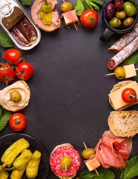 Mix van verschillende snacks en hapjes. Spaanse tapas op een zwarte steenachtergrond.