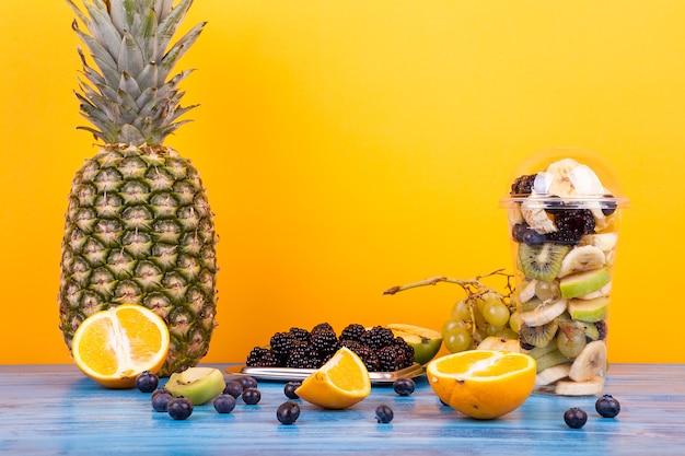 Mix van verschillende soorten fruit als salade in kopjes met vers fruit op houten tafel. Gezonde verse smakelijke woestijn?