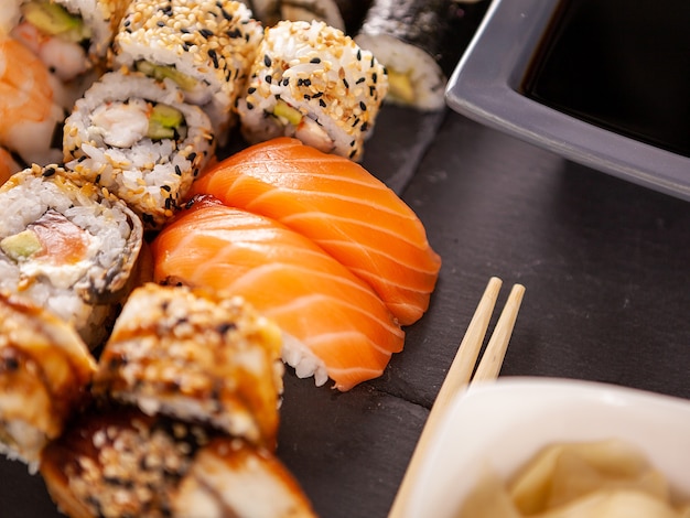 Mix variety of sushi rolls on black stone backgorund in studio