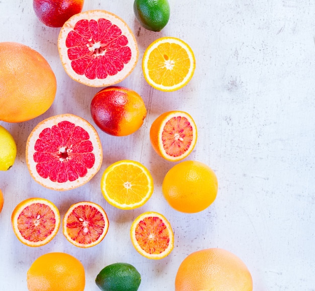 Mix of whole and cut citruses on white wooden table