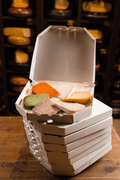 Mix of young Gouda young goat lavander cheese and green and red pesto cheeses in the cardboard box Creative idea for advertising a cheese shop