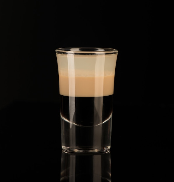 Mixed alcoholic liquor in a shot glass isolated on a black background