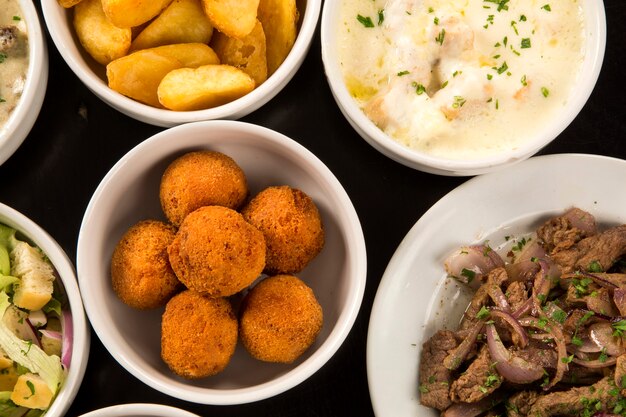 Смешанные бразильские закуски, включая выпечку, жареную курицу, салаты, супы, картофель фри и кибе.