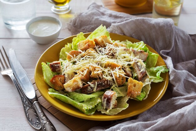 Mixed Caesar Salad with chicken on a yellow plate