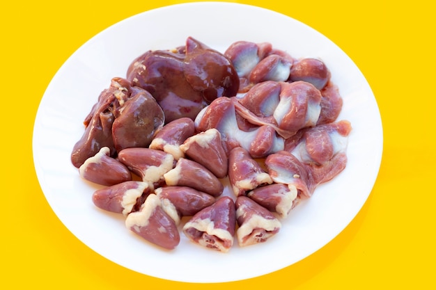 Mixed chicken entrails in white plate on yellow background.