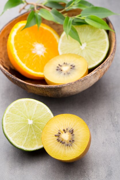 Mixed citrus fruit lemons, orange, kiwi, limes on a gray background.