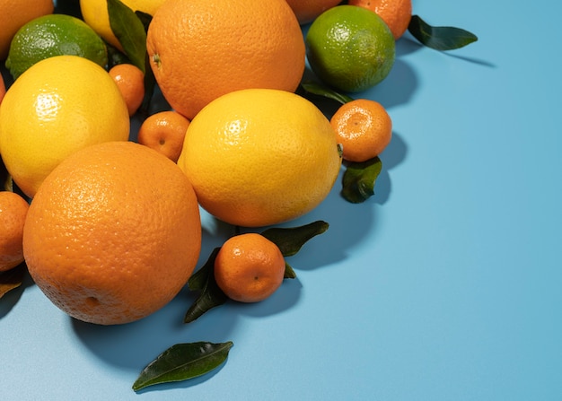 Mixed citrus fruit with leafs in a blue background with copy space