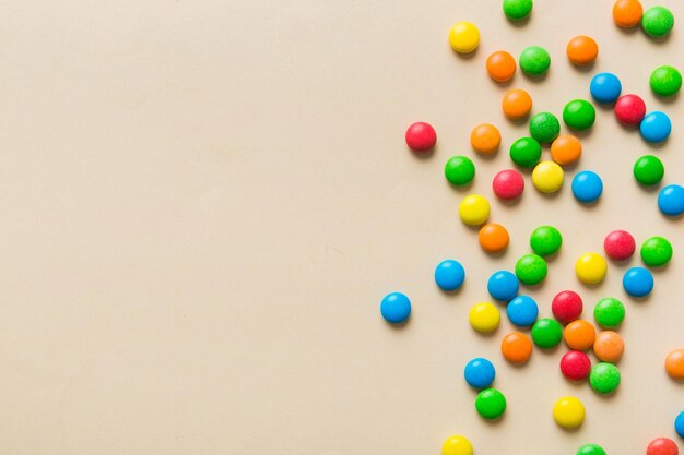 Mixed collection of colorful candy on colored background Flat lay top view frame of colorful chocolate coated candy