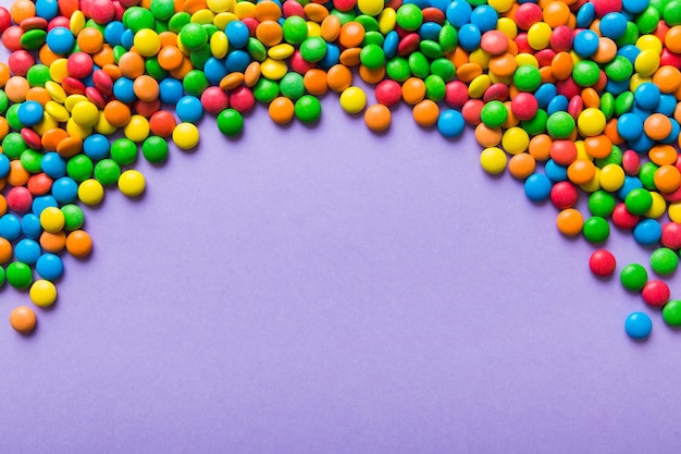 Mixed collection of colorful candy on colored background Flat lay top view frame of colorful chocolate coated candy