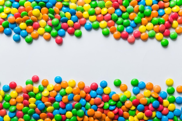 Mixed collection of colorful candy on colored background Flat lay top view frame of colorful chocolate coated candy