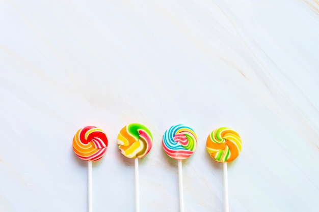 Mixed colorful lollipops on white marble table with free copy space background.