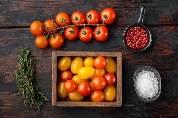 Photo mixed colour cherry tomatoes in wooden tray, on old wooden table, top view