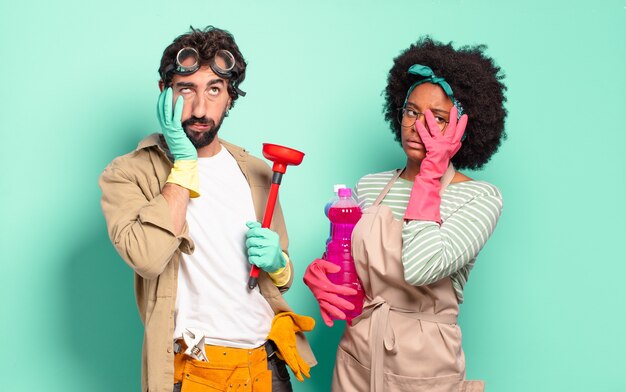 Mixed couple feeling bored, frustrated and sleepy after a tiresome, dull and tedious task, holding face with hand. housekeeping concept.. home repairs concept