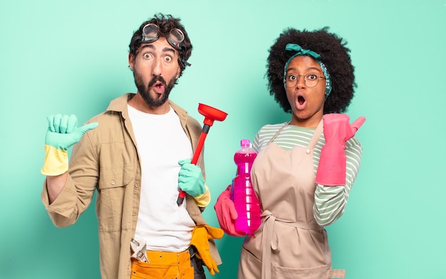 Mixed couple looking astonished in disbelief, pointing at object on the side and saying wow, unbelievable. housekeeping concept.. home repairs concept