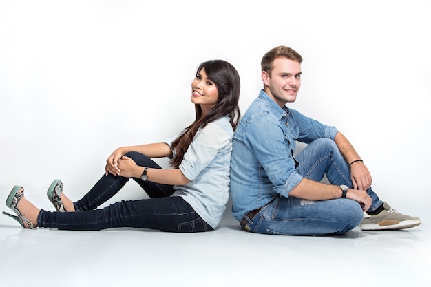 Mixed couple sitting back to back on the floor