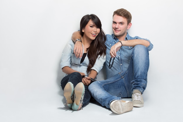 Mixed couple sitting on the floor. man embracing woman