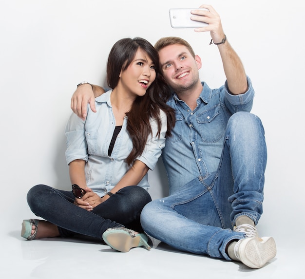 Mixed couple sitting on the floor taking self camera together